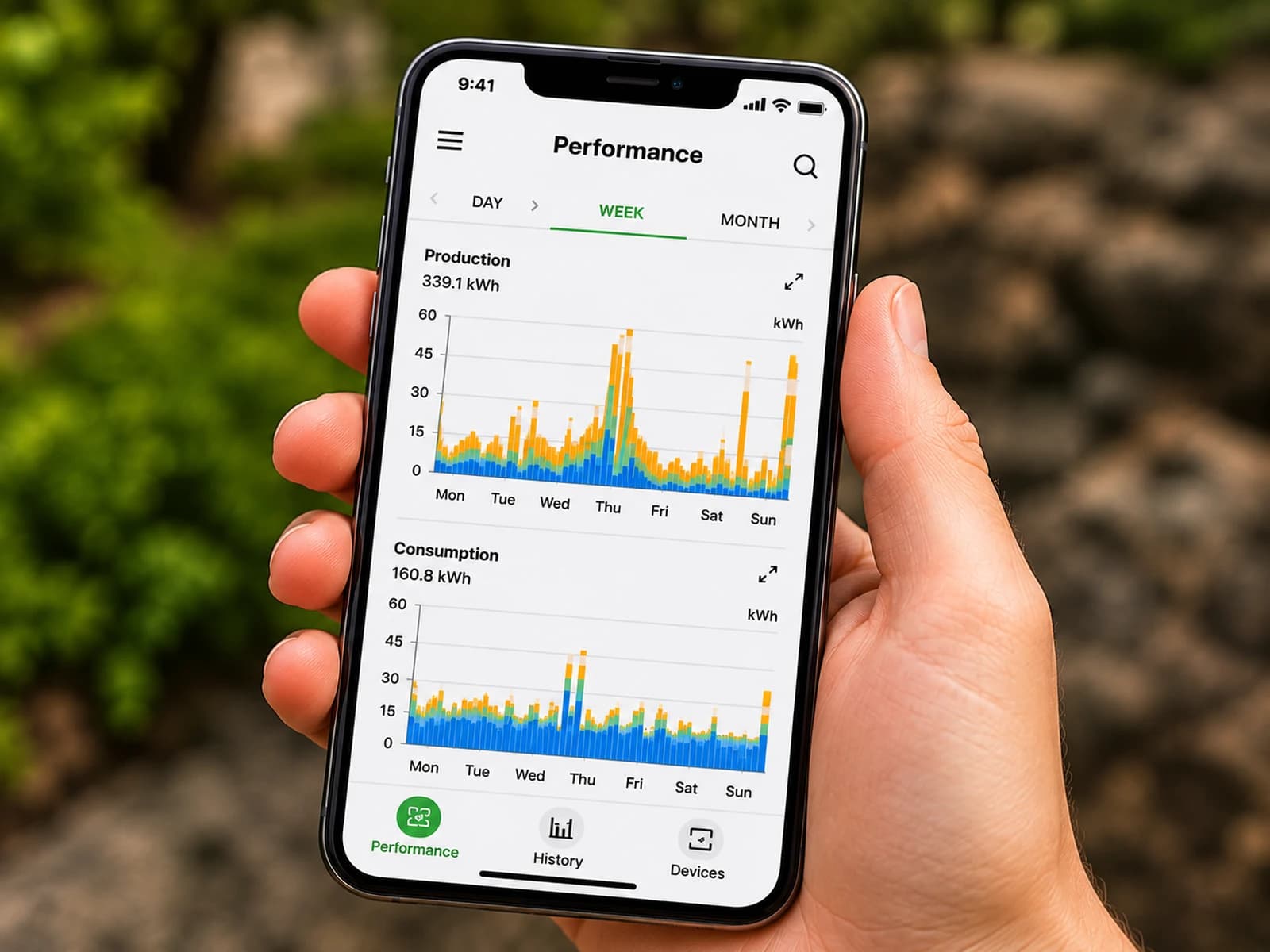 Hand holding a phone showing solar production monitoring app